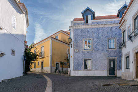 Pedestrian street in Cascais featuring a traditional yellow Portuguese house and a blue tile facade along Rua dos Navegantes.の写真素材