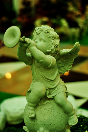 Cupid's statue, musician on a circular pedestal in the garden.の写真素材