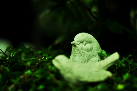 The white bird sculpture is staring at the green shrubs.の写真素材
