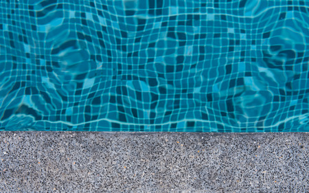 The blur caused by the water wave in the mosaic tile pool,have concrete edge made of black gravel.の写真素材
