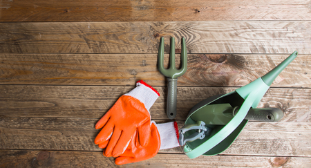 Gardening equipment Including a fork, spoon, watering tank, pruning scissors and gloves. All are laid on a vintage brown wood floor.の写真素材