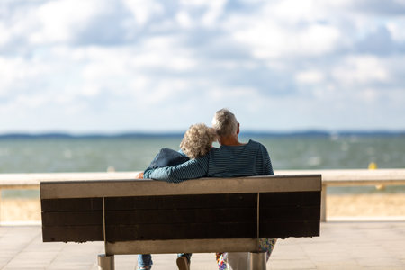 senior couple sitting on a bench looking at the seaの写真素材