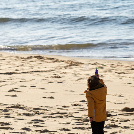 boy on the beach blowing bubbles with a gunの写真素材