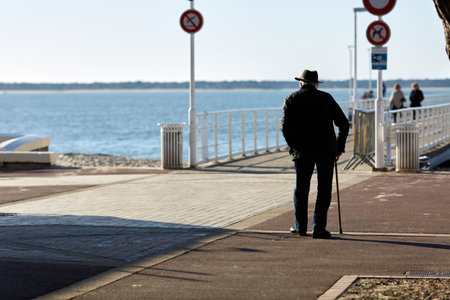 elderly man walking on the boardwalk with a caneの写真素材