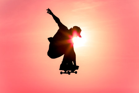 skateborder silhouette jumping facing the sun