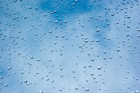 a view of some rain drops in the window with the sky at the backgroundの写真素材