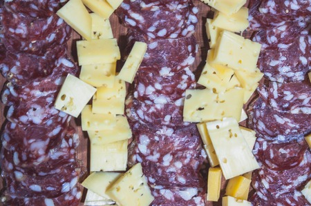 argentinian cheese and salami on a kitchen wooden board o a white background. Top view with copy...