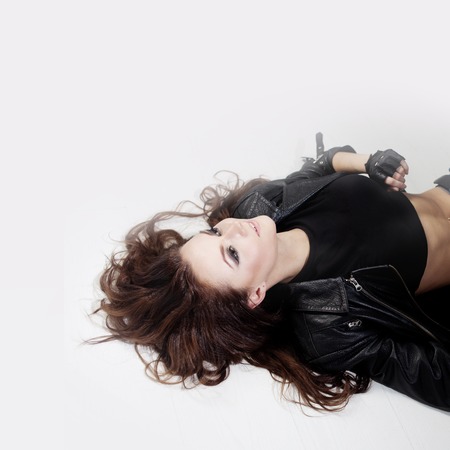 beautiful young woman in a leather jacket sittingの写真素材