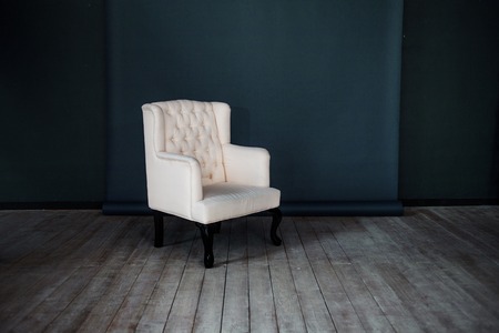 One classic armchair against a dark blue wall and floor.の写真素材
