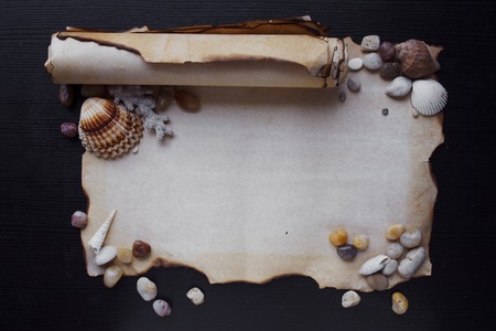 Old scroll of parchment with sea pebbles and seashellsの写真素材