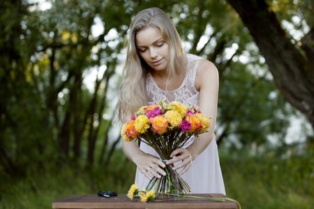 Young beautiful woman florist. The girl in the Park draws a bouquetの写真素材