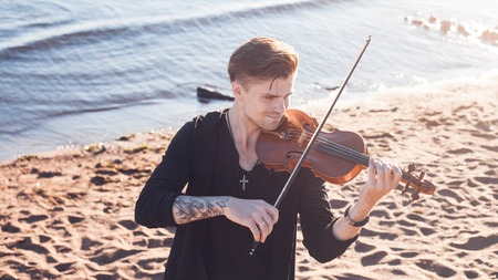 Violinist playing a violin, on the background of the seaの写真素材