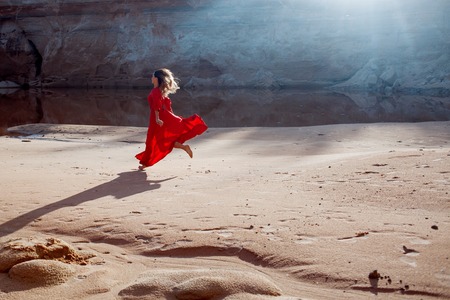 Woman in red waving dress with flying fabricの写真素材
