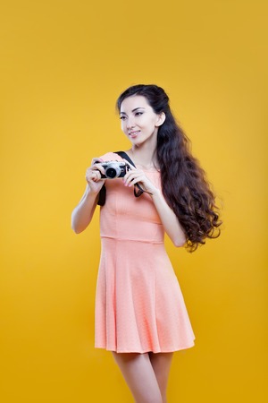 Fashion asian girl with the camera, portrait on yellow backgroundの写真素材
