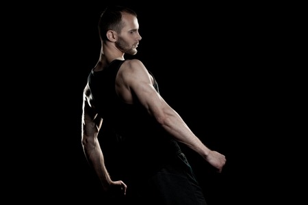 muscular man on a black background, clasps hands in a fistの写真素材