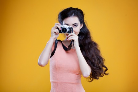 Fashion asian girl with the camera, portrait on yellow background
