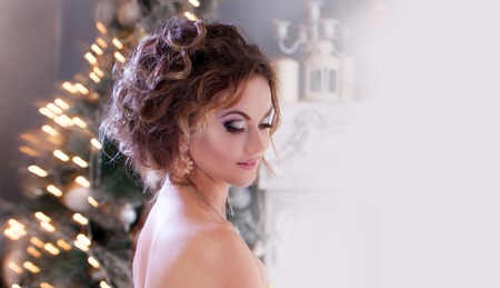 woman in evening dress  over christmas tree lights backgroundの写真素材