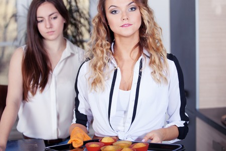 A young woman with baked cupcakes in her kitchen