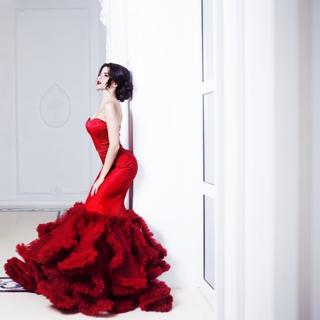 Beauty Brunette model woman in  evening red dress. Beautiful fashion luxury makeup and hairstyleの写真素材
