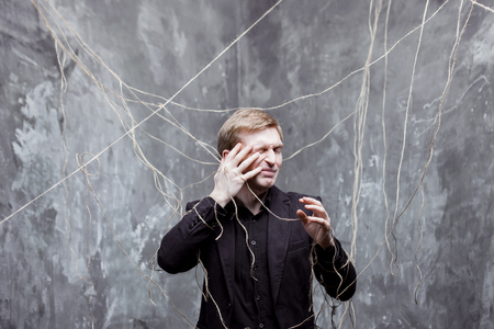 Young man in a black suit got caught in the web.の写真素材