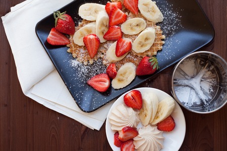 Waffles with fresh strawberries and bananas on rustic wooden backgroundの写真素材