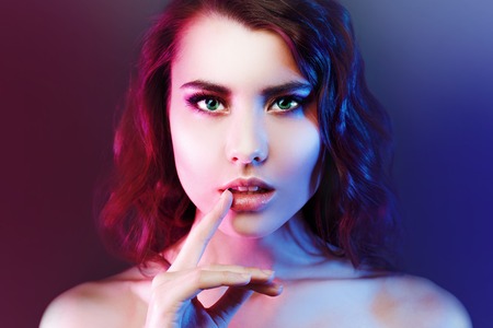 Portrait of young beautiful girl with dark hair, amid the spotlight. The effect of toning, night club.の写真素材