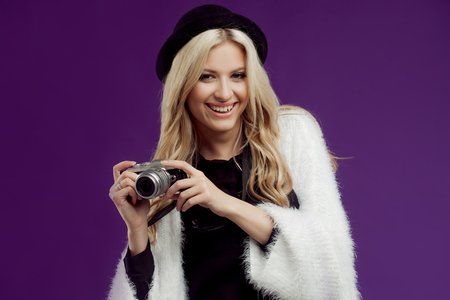 Fashion young girl makes photo. Purple background. Photographerの写真素材