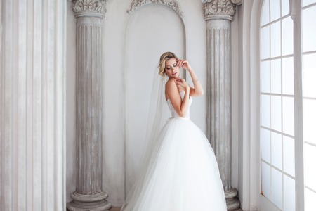 Charming young bride in luxurious wedding dress near the window. Pretty girl, photo Studioの写真素材