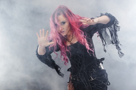 Halloween. Witch creates magic. Attractive woman with red hair in witches costume