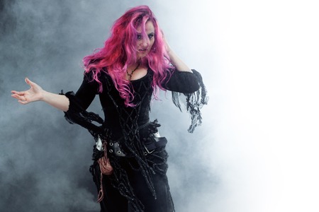 Halloween. Witch creates magic. Attractive woman with red hair in witches costumeの写真素材