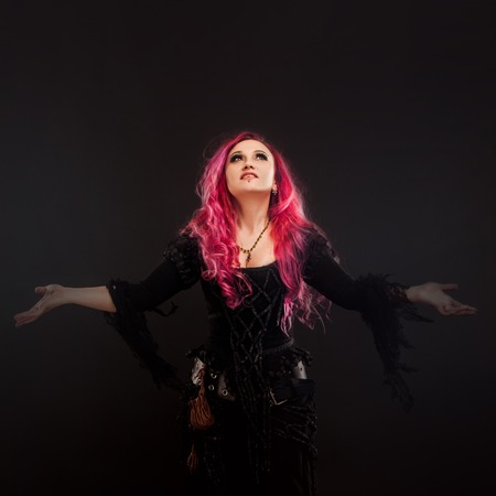 Halloween. Witch creates magic. Attractive woman with red hair in witches costume