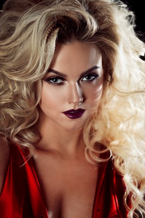 Fashion photo of young magnificent woman in red dress. Studio portrait. Seductive blonde in dress with fluffy skirtの写真素材