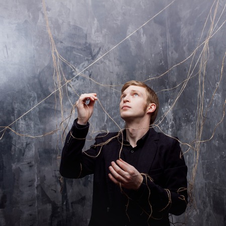 Young man in a black suit got caught in the web.の写真素材