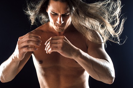 muscular man, clasps hands in fist, black backgroundの写真素材