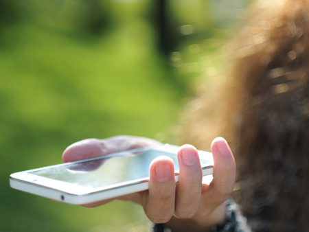 A young girl is using smartphone outdoorsの写真素材