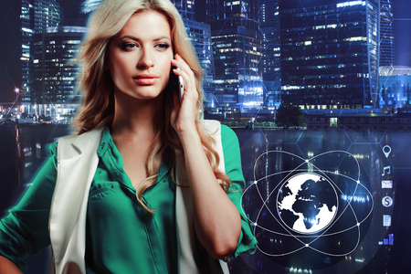 Young and attractive blonde girl talking on the phone on technology background in blue tonesの写真素材