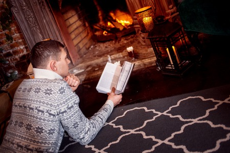 Man and woman in knitted sweater sitting on the floor by the fireplaceの写真素材