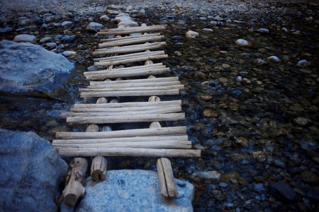 wooden makeshift bridge over a small riverの写真素材