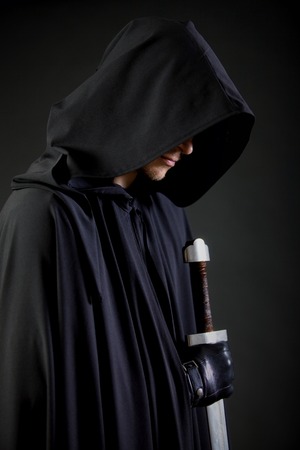 Portrait of a courageous warrior wanderer in a black cloak and sword in hand.の写真素材