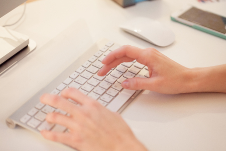 Closeup of a female hands typing on laptop keyboard in the officeの写真素材