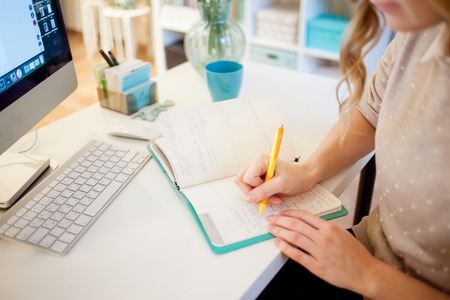 Young businesswoman sitting at desk and working. Beautiful woman fills plannerの写真素材