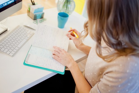Young businesswoman sitting at desk and working. Beautiful woman fills plannerの写真素材