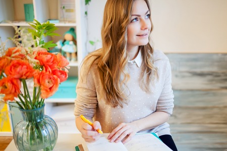 Young businesswoman sitting at desk and working. Beautiful woman fills planner
