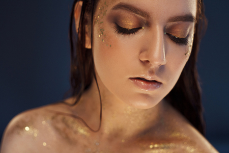 Close up portrait of beautiful woman with creative gold make upの写真素材