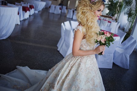 Young fashion bride with perfect skin and make up, curly hair, flowers and tiara on the head, indoorsの写真素材