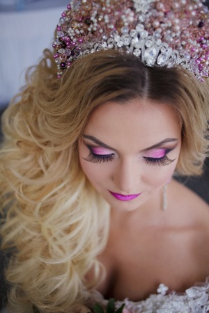 Young fashion bride with perfect skin and make up, curly hair, flowers and tiara on the headの写真素材