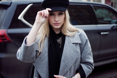 Young, hip and attractive blonde walking around the city, girl in a stylish hat and a gray coatの写真素材