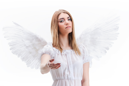 An angel from heaven gives you a hand. Young, wonderful blonde girl in the image of an angel with white wings.の写真素材
