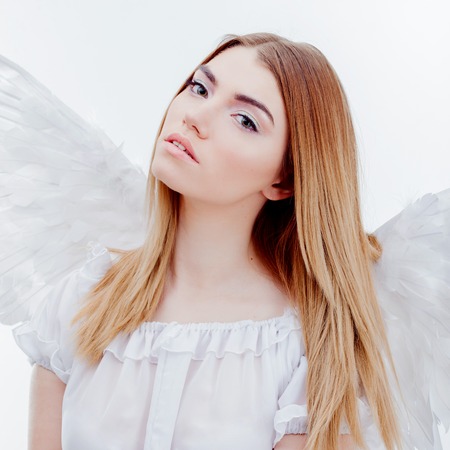 An angel from heaven. Young, wonderful blonde girl in the image of an angel with white wings. Portrait close-upの写真素材