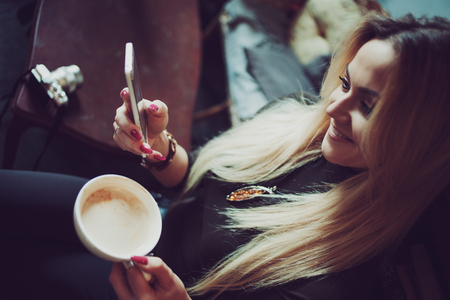Young female freelancer chatting on mobile phone while sitting on the couch in vintage cafeの写真素材